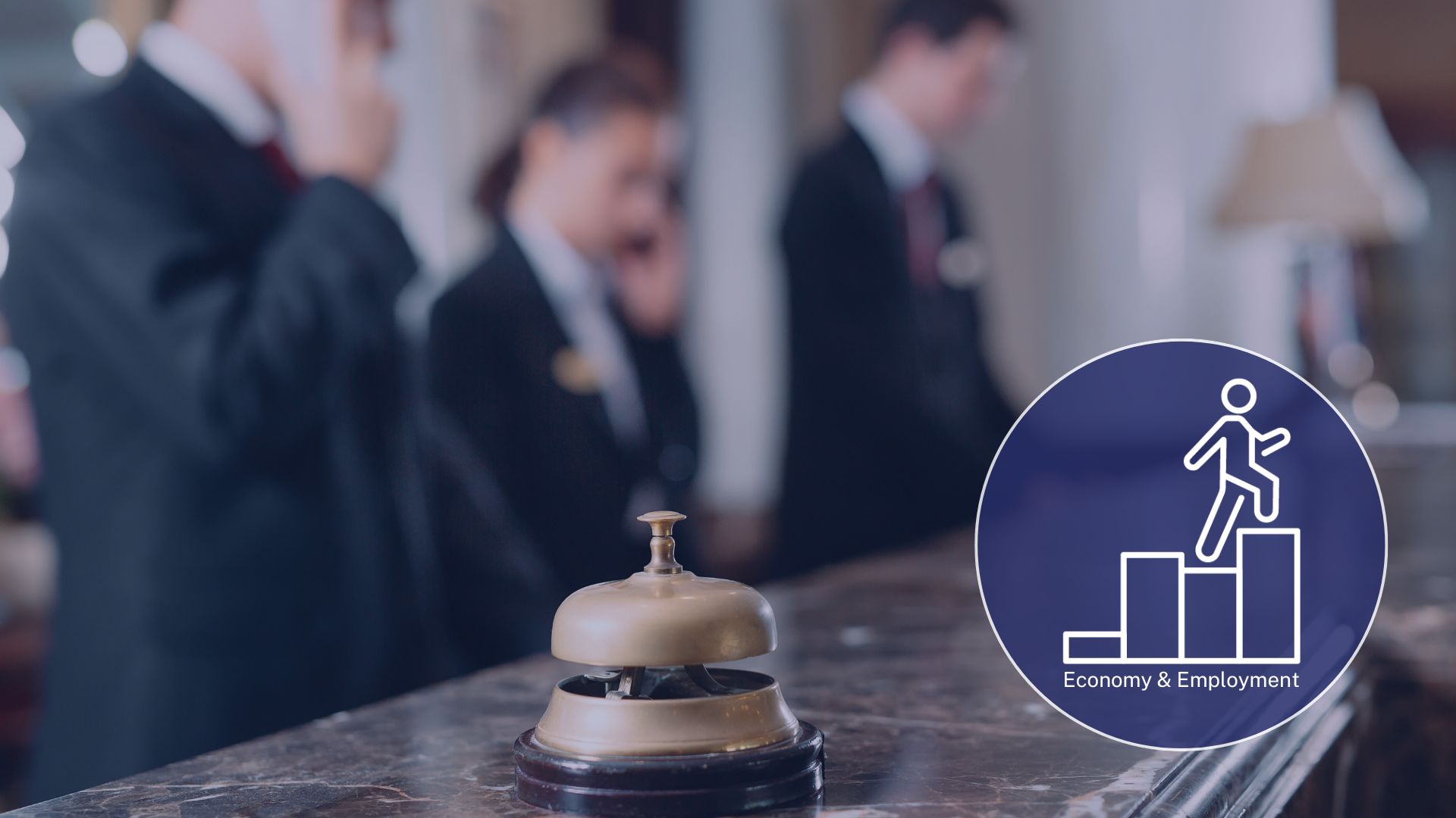 Soft focus photo of a hotel reception desk. There is a bell in sharp focus in the foreground.